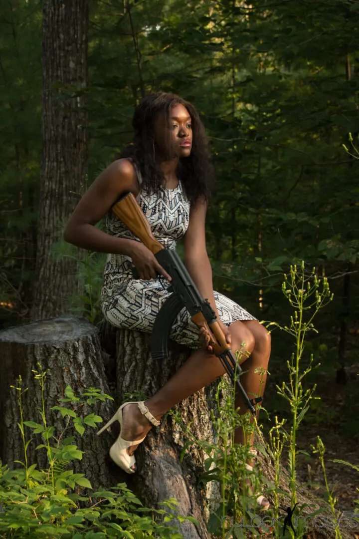 A woman sitting on top of a tree holding an ar-1 5.